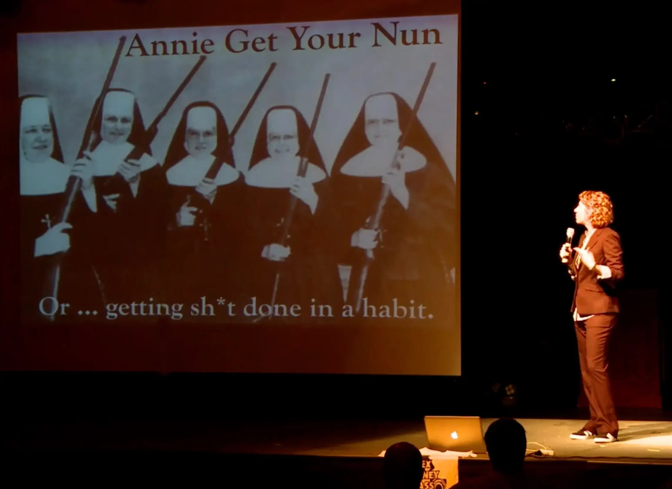 Michele Stowe of Skyrocket Coaching speaking on stage "Annie Get Your Nun"